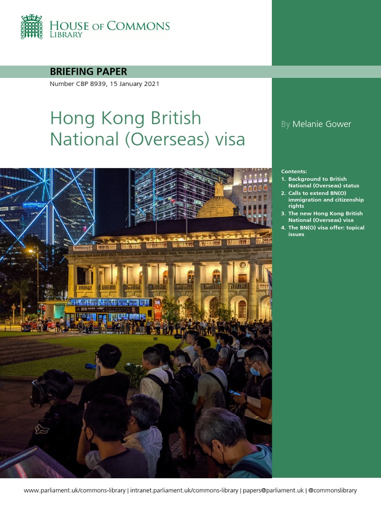 A group of people wearing masks and backpacks gather in front of a historic building illuminated at night, with modern skyscrapers in the background, under a headline about the Hong Kong British National (Overseas) visa policy.